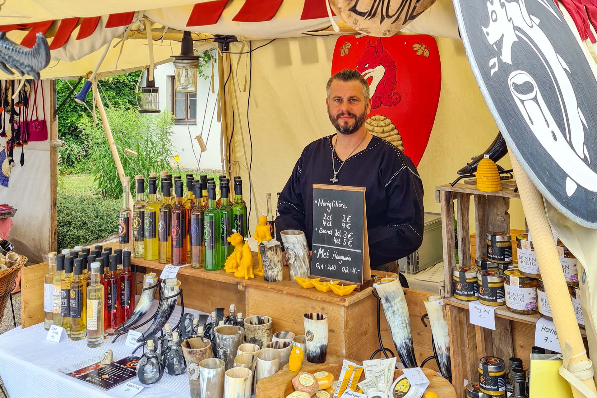 Wikinger am Mittelaltermarktstand mit Metflaschen und Honigprodukten